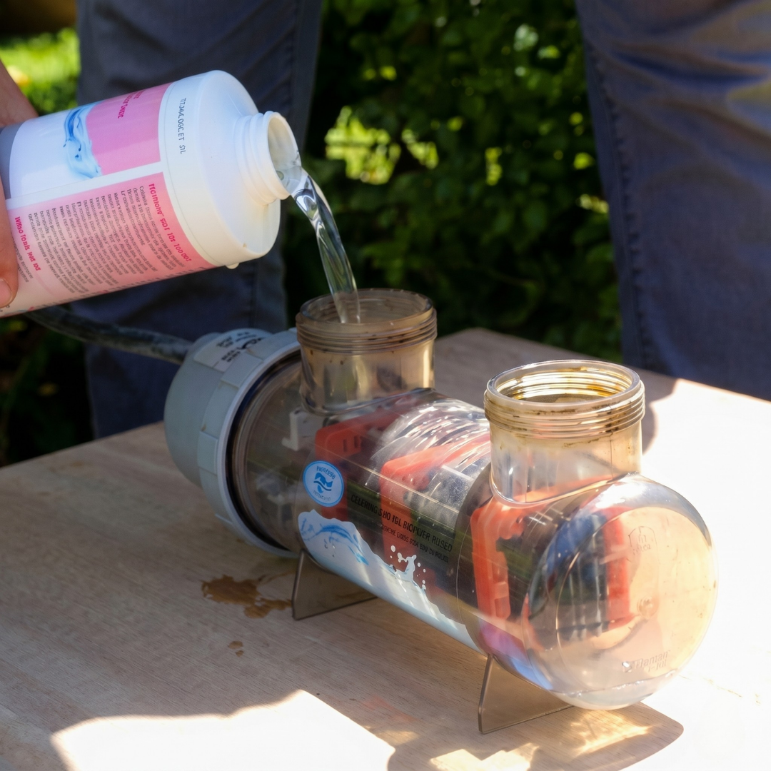 A person pouring BioGuard Salt Cell Cleaner into a salt chlorinator cell to remove calcium scale buildup. This specialized solution helps maintain pool salt water systems without damaging the plates.