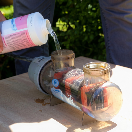 A person pouring BioGuard Salt Cell Cleaner into a salt chlorinator cell to remove calcium scale buildup. This specialized solution helps maintain pool salt water systems without damaging the plates.