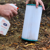 A person spraying BioGuard SPA Filter Renew onto a white pleated spa cartridge filter to remove oils and scale. This spray-on cleaner is an essential part of regular hot tub maintenance and filter deep cleaning.