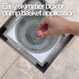A hand placing a BioGuard Mini Cube Water Clarifier block into a swimming pool skimmer box for easy application and steady release water treatment.