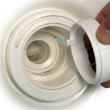 Close-up view of a hand inserting a light grey plastic adapter ring into a hot tub jet body socket, with a blue arrow indicating the alignment tab fitting into the wall notch.