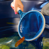 Person using the Life Spa Scoop skimmer net to remove floating leaves from a blue hot tub.