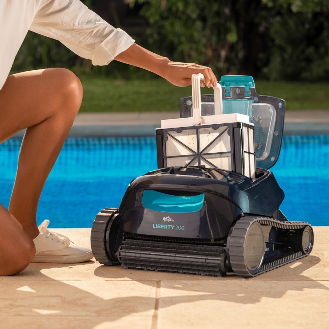Lifestyle view of a person kneeling poolside lifting the top-access fine mesh filter basket by its handle out of the open Maytronics Dolphin Liberty 200 robotic pool cleaner.