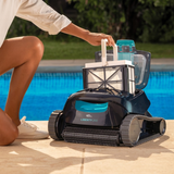 Lifestyle view of a person kneeling poolside lifting the top-access fine mesh filter basket by its handle out of the open Maytronics Dolphin Liberty 200 robotic pool cleaner.