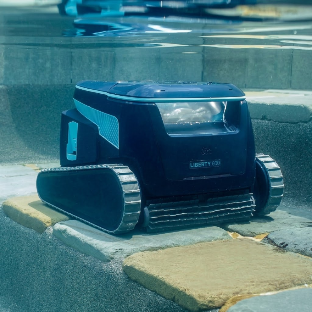 Underwater front lifestyle view of the Maytronics Dolphin Liberty 600 robotic pool cleaner parked on stone pool steps near the water surface.