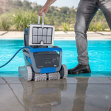 Poolside lifestyle view of a person pulling the top-loading fine filter basket out of the dark grey Maytronics Dolphin M 700 robotic pool cleaner.