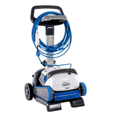 Three-quarter studio view of a Maytronics Dolphin S200 robotic pool cleaner resting on its transport caddy on an isolated white background, displaying its white and blue chassis, front active scrubbing brush, blue tracks, coiled blue floating cable with anti-tangle swivel, power supply holder tray, and wheeled caddy frame.
