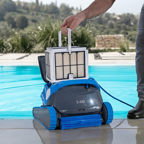 Poolside lifestyle view of a person lifting the top-access fine filter basket out of the dark grey and blue Maytronics Dolphin S 400 robotic pool cleaner.