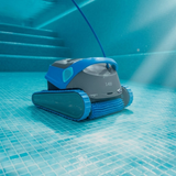Underwater action shot of the dark grey and blue Maytronics Dolphin S 400 robotic pool cleaner operating on a tiled pool floor near underwater steps, showing its blue active front scrubbing brush and power cable.