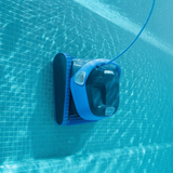 Underwater view of the dark grey and blue Maytronics Dolphin S 400 robotic pool cleaner climbing vertically up a blue tiled pool wall with its blue power cable attached.