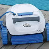 Front close-up view of the white and light blue Maytronics Dolphin S 50 robotic pool cleaner resting on wooden decking next to a pool, showcasing its blue front scrubbing brush and continuous tracks.