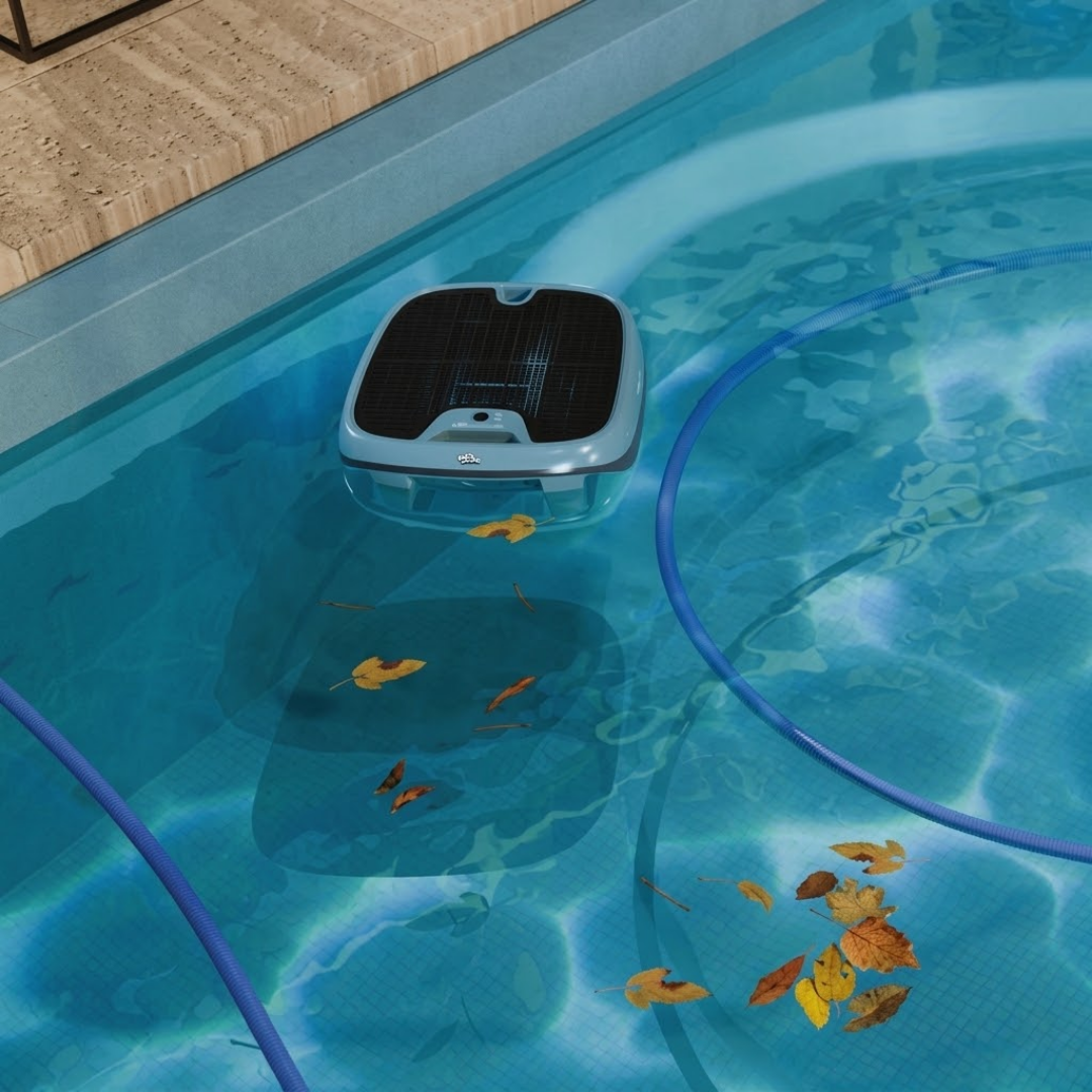 High-angle lifestyle view of the Maytronics Dolphin Skimmi 300 robotic pool skimmer floating near the tiled edge of a swimming pool, collecting leaves floating on clear blue water.
