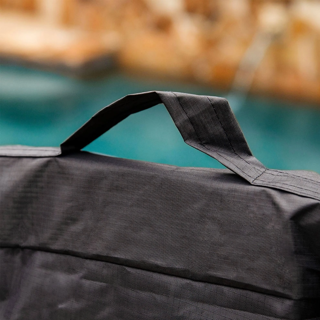 Close-up detail studio photo of the reinforced top nylon webbing handle stitched onto the black weather-resistant Maytronics Dolphin transport caddy cover, showing textured fabric weave against a blurred outdoor background.