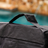 Close-up detail studio photo of the reinforced top nylon webbing handle stitched onto the black weather-resistant Maytronics Dolphin transport caddy cover, showing textured fabric weave against a blurred outdoor background.