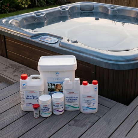 Poppits Peroxsil chlorine-free spa startup pack including Peroxsil 395 sanitiser, One Step Water Prep, Pool and Spa Complete, Quick Fix, Filter Cartridge Cleaner, and test strips arranged on a grey timber deck next to an outdoor hot tub.