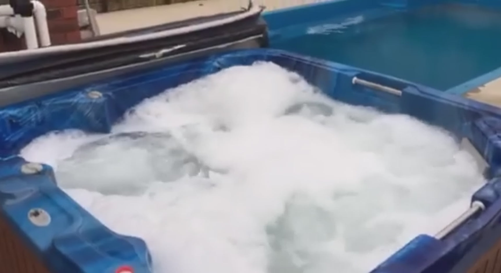 BioGuard SPA Foam Go poured into a foaming blue hot tub, instantly dissolving thick white foam to reveal clear water