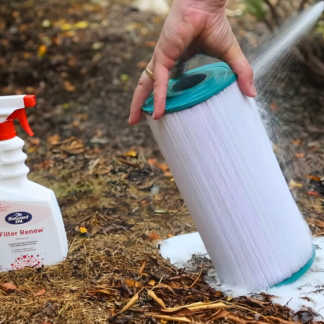 A person using a garden hose to rinse a pleated spa cartridge filter after applying BioGuard SPA Filter Renew. The foaming action shows the cleaner lifting dirt, oils, and scale from the filter pleats during a deep clean.