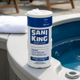 Close-up view of a Sani-King Adjust-A-Flo bromine sanitizer dispenser sitting on the coping edge of an outdoor hot tub.