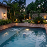 Small Sani-King chemical dispenser floating in the center of an illuminated backyard hot tub at dusk.