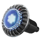 Angled front-facing perspective view of an active Spa Electrics EMF Multi Plus LED pool light displaying blue illumination, textured honeycomb face pattern, and clear fluted outer rim isolated on white.