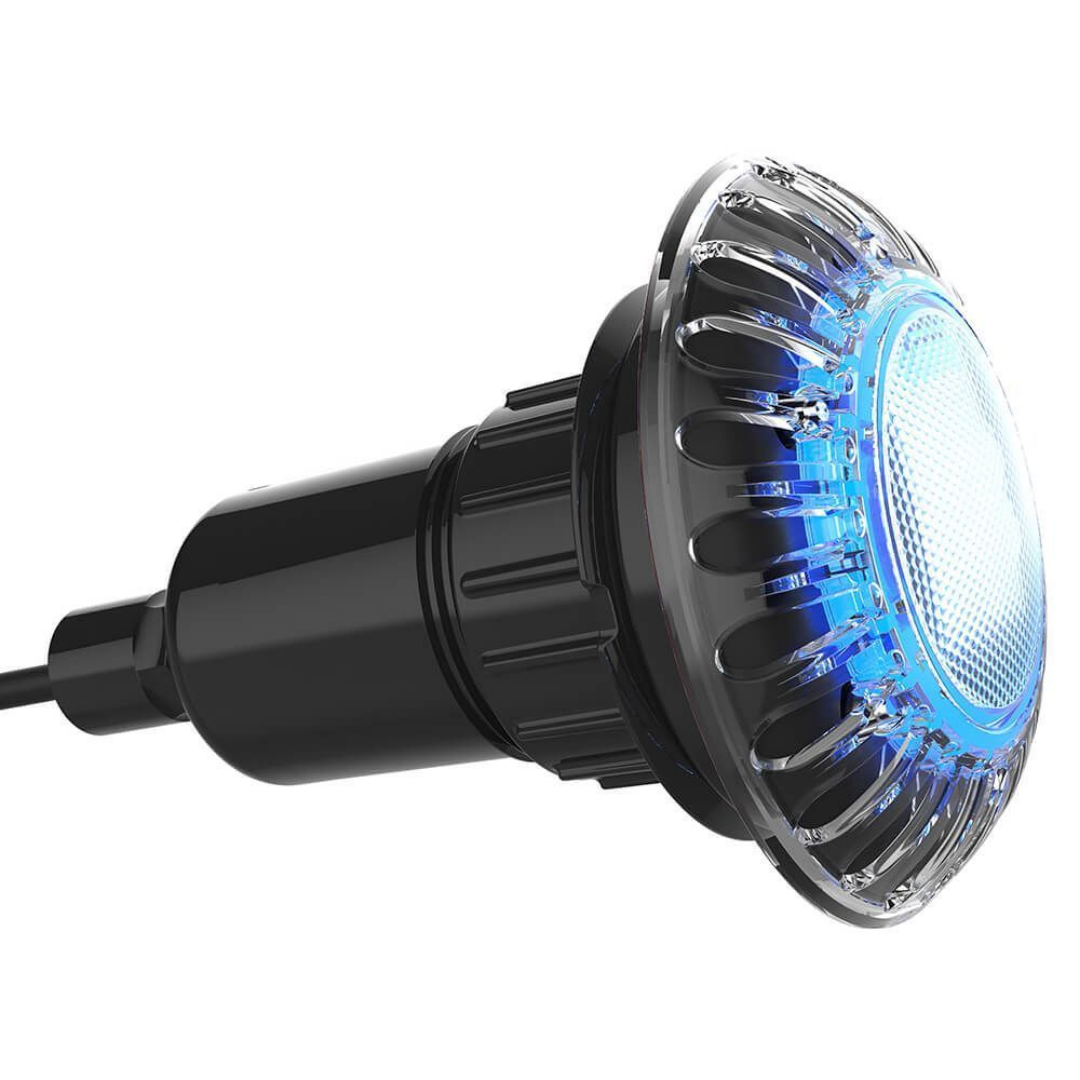 Three-quarter side perspective view of an illuminated Spa Electrics EMF Multi Plus LED pool light showing the blue illuminated front lens, clear ribbed trim, and black rear housing assembly with cable gland.