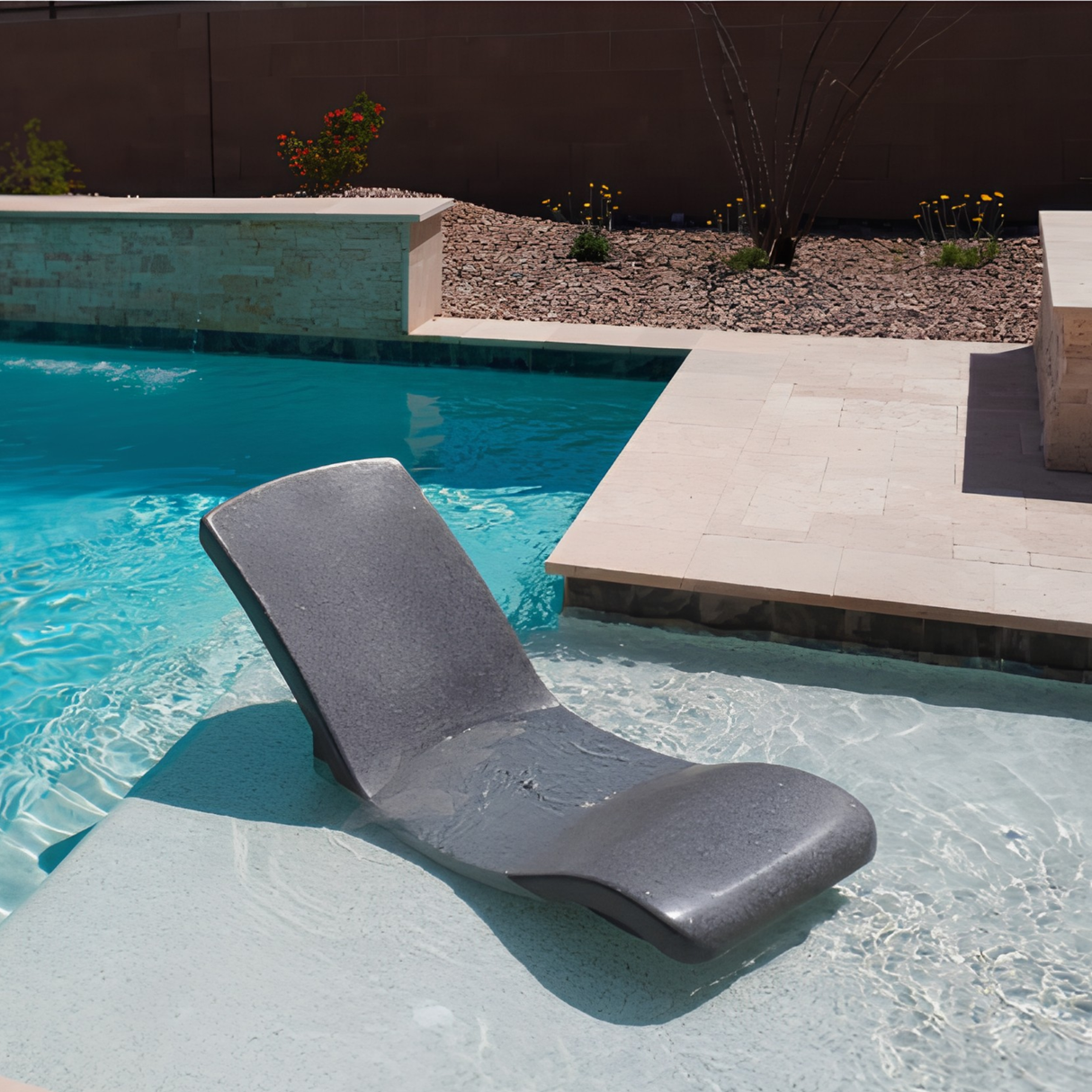 An empty S.R. Smith Destination Series in-pool rocking lounge chair in Starry Night dark grey finish sitting on a shallow pool sun shelf.
