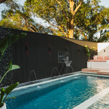 Luxury inground swimming pool featuring an S.R. Smith basketball hoop mounted against a modern black feature wall with deck water jets