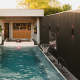 S.R. Smith pool basketball hoop installed alongside a luxury inground pool with deck jets, rain curtain waterfall, and an outdoor swim-up bar.