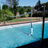 Outdoor lifestyle photo showing the S.R. Smith Swim N' Spike volleyball net stretched across a backyard residential swimming pool, anchored into deck posts.