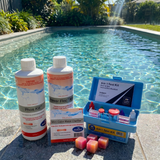 A swimming pool chemical kit on the edge of a clear blue pool, featuring BioGuard Phos Kill, Power Floc Max, Mini Cube Water Clarifier cubes, and an Aussie Gold 4-in-1 Test Kit.