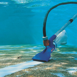 Underwater view of a blue Swimsafe Supa-Vac pool cleaner vacuuming a thick layer of dirt and debris from the bottom of a swimming pool, leaving a clean white path behind it.