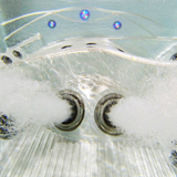 Underwater view of two Ultra Blaster 7 SS Graphite spa jets installed in a hot tub seat, actively spraying aerated streams of water into the pool.