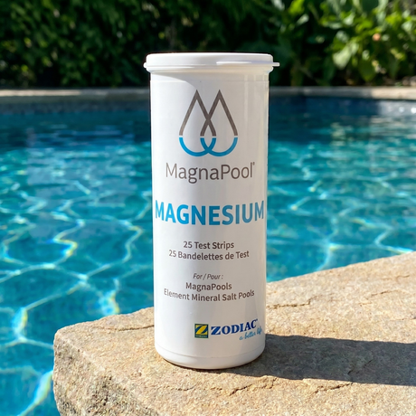 A bottle of Zodiac MagnaPool Magnesium Test Strips sitting on a stone poolside coping next to a clear blue mineral swimming pool.